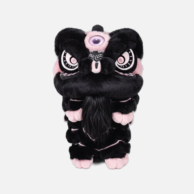 A black plush lion dance costume or character toy with pink accents, large white eyes with black outlines, and a purple eye patch, centered on a light gray background.