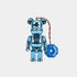 A metallic blue Bearbrick figure with a colorful braided string and a blue donut-shaped tag that reads &