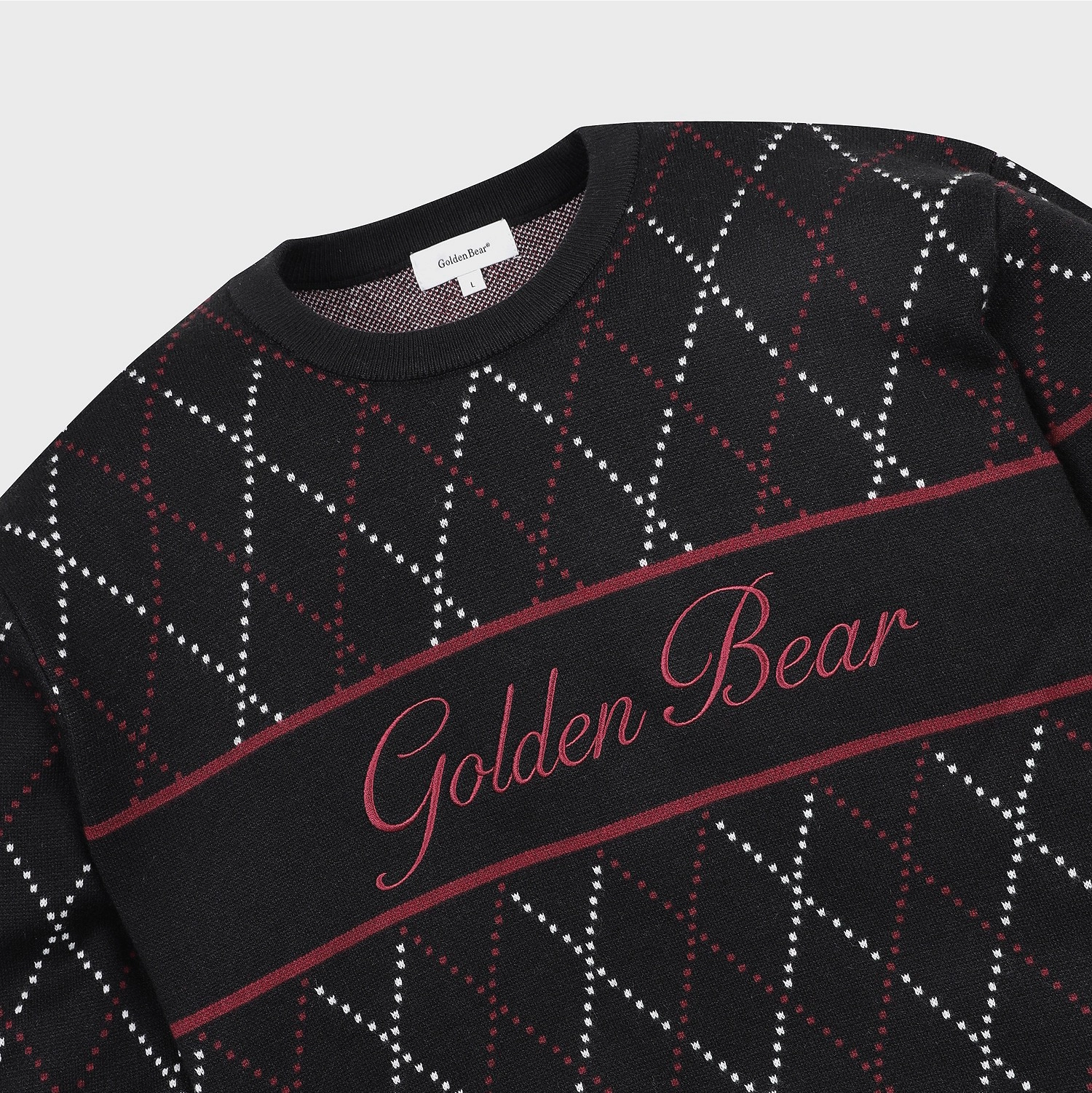 A close-up of a black crewneck sweater featuring a red and white argyle pattern and a central horizontal band with 'Golden Bear' embroidered in red script.