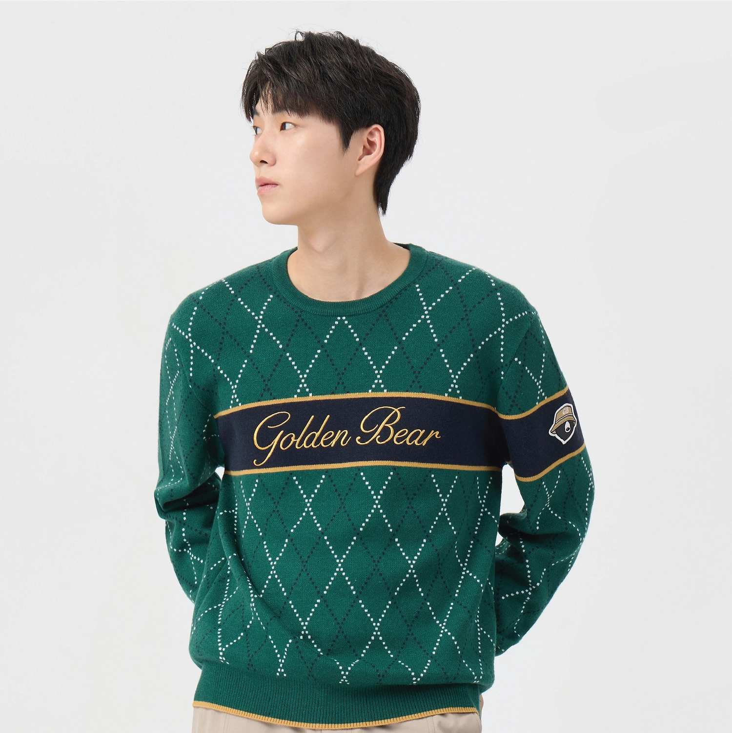 A man wearing a green argyle sweater with a navy blue chest stripe featuring gold trim and the words 'Golden Bear'.