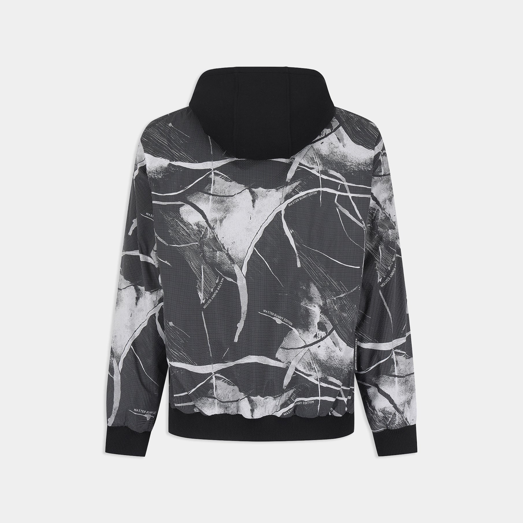 A black and white abstract paint splatter print hoodie shown from the back, featuring a solid black hood and ribbed cuffs and hem, set against a light gray background.