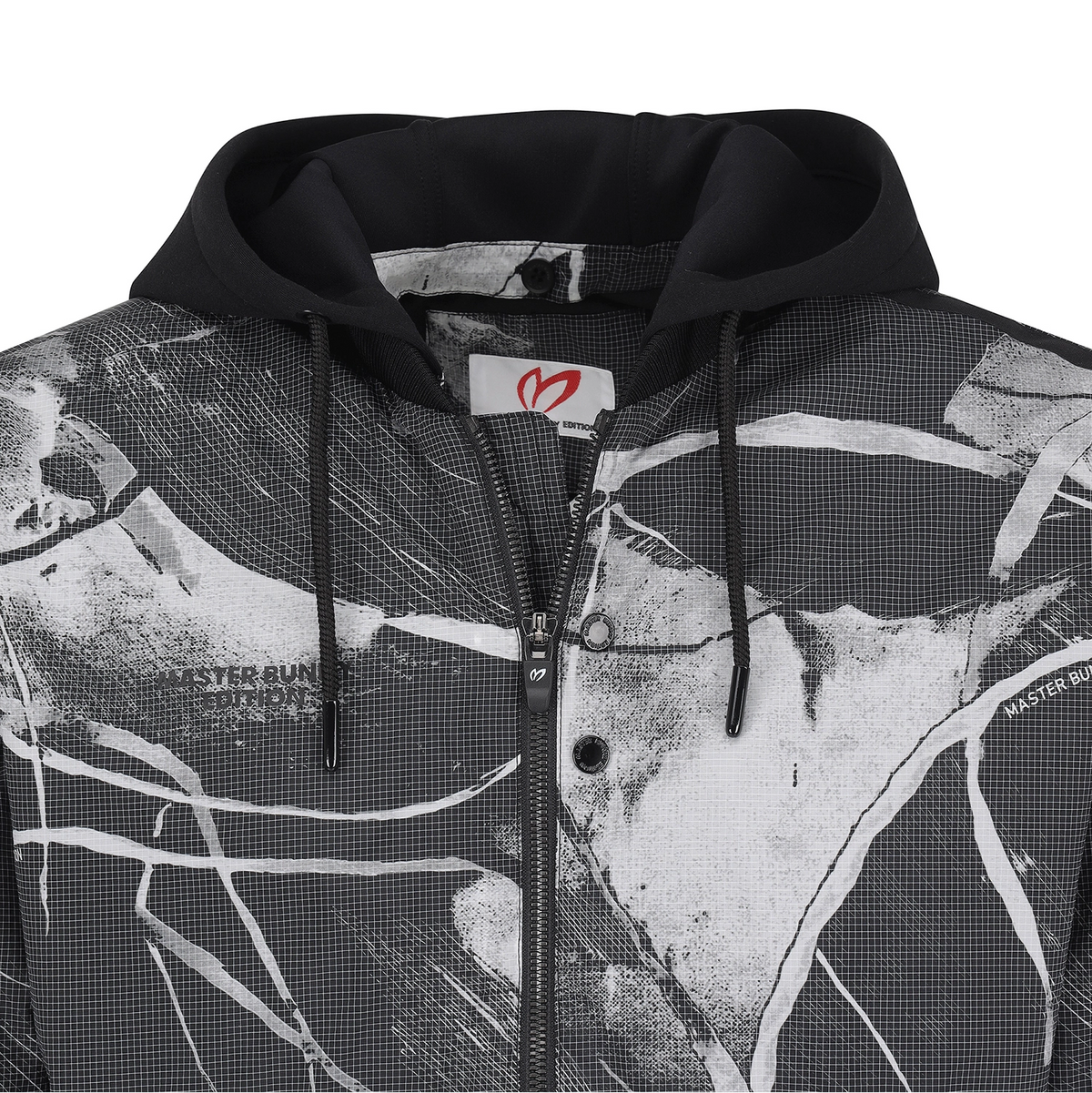 A close-up of a black and white graphic zip-up hoodie with a black hood and drawstrings, featuring a white brand label with a red logo.