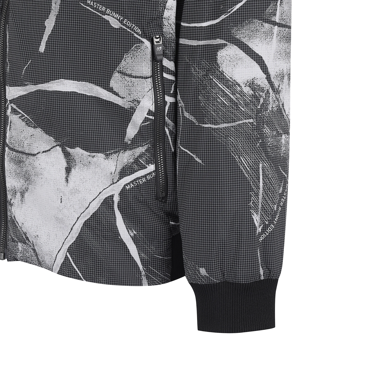 Close-up of a black and white abstract patterned jacket with a ribbed black cuff and a vertical zipper pocket.