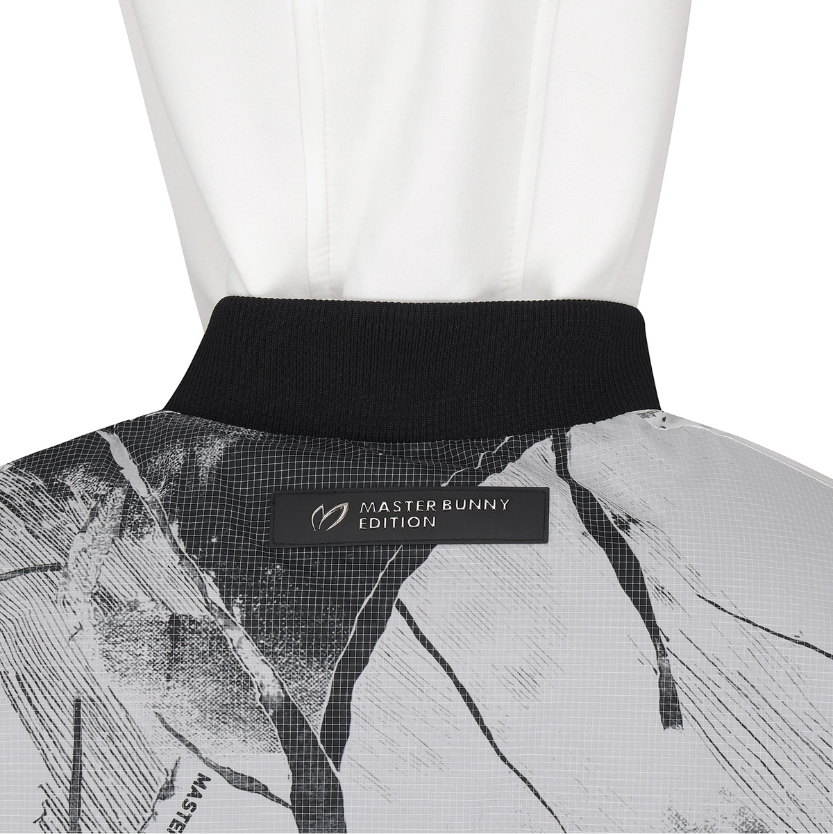 Close-up of the back collar of a white hooded jacket with a black ribbed neckband and a black Master Bunny Edition label, over a white mannequin.