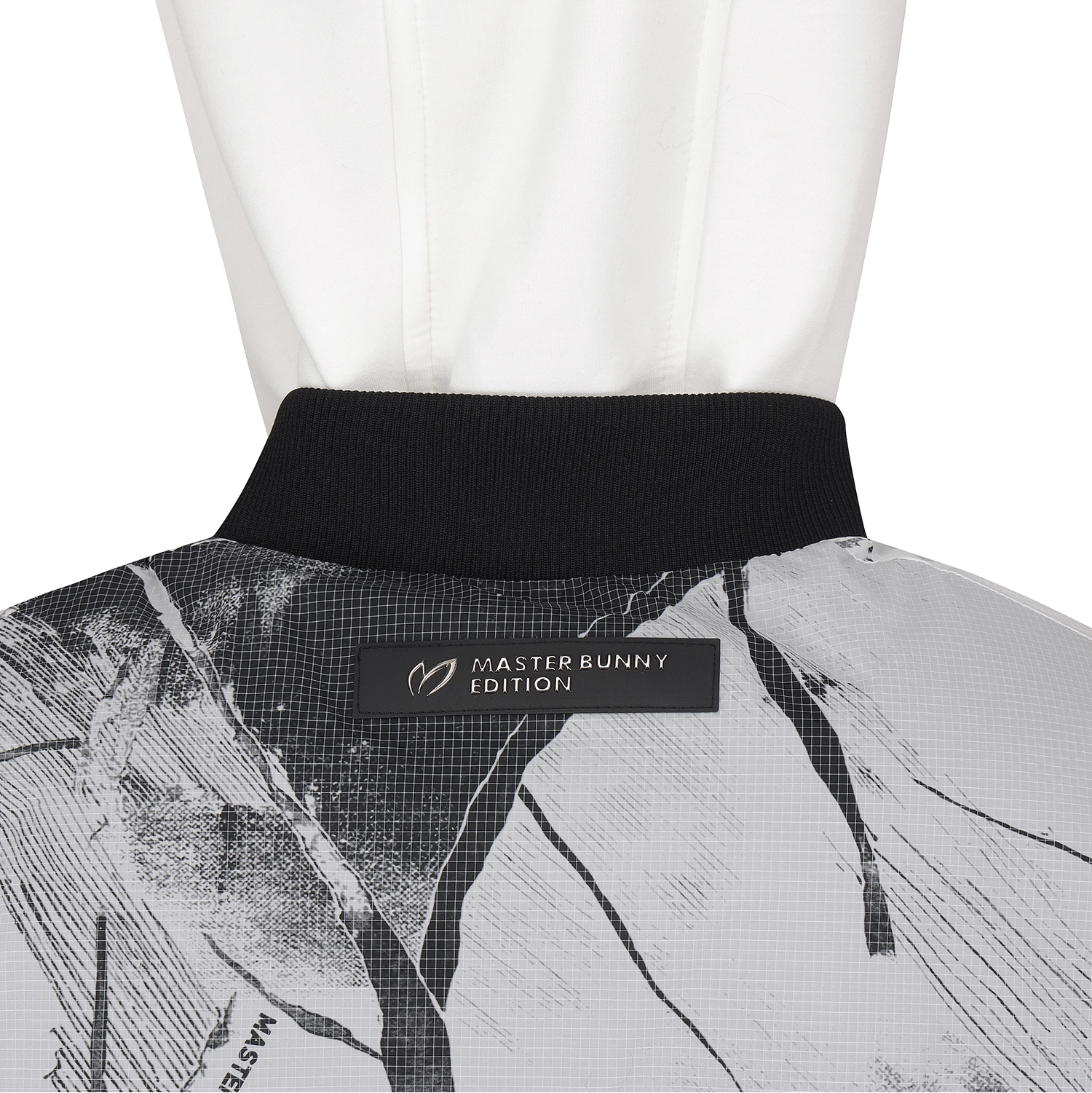 Close-up of the back collar of a white hooded jacket with a black ribbed neckband and a black Master Bunny Edition label, over a white mannequin.