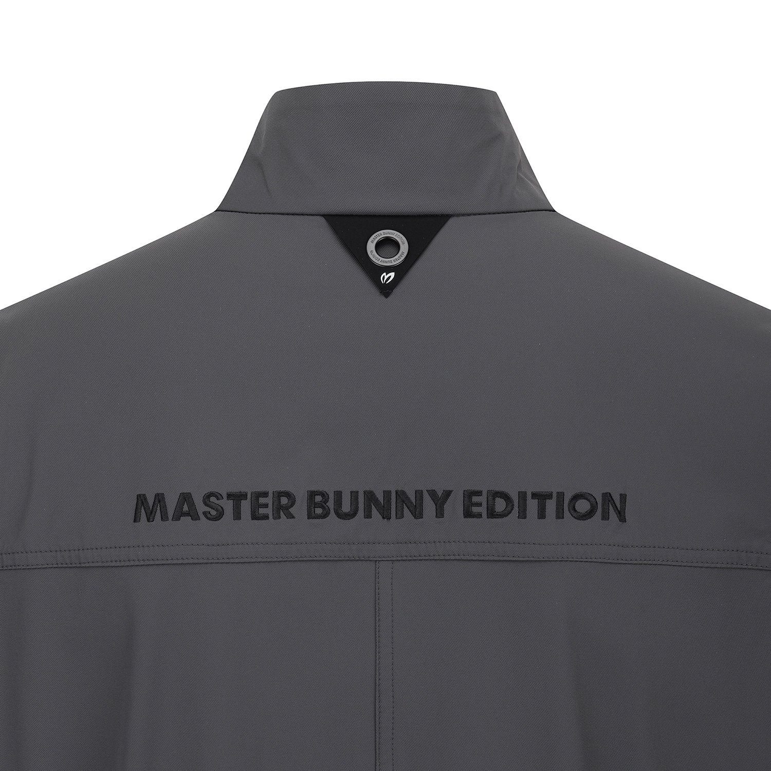 Close-up back view of a dark gray jacket with 'MASTER BUNNY EDITION' printed across the upper back and a black triangular collar detail at the neck.