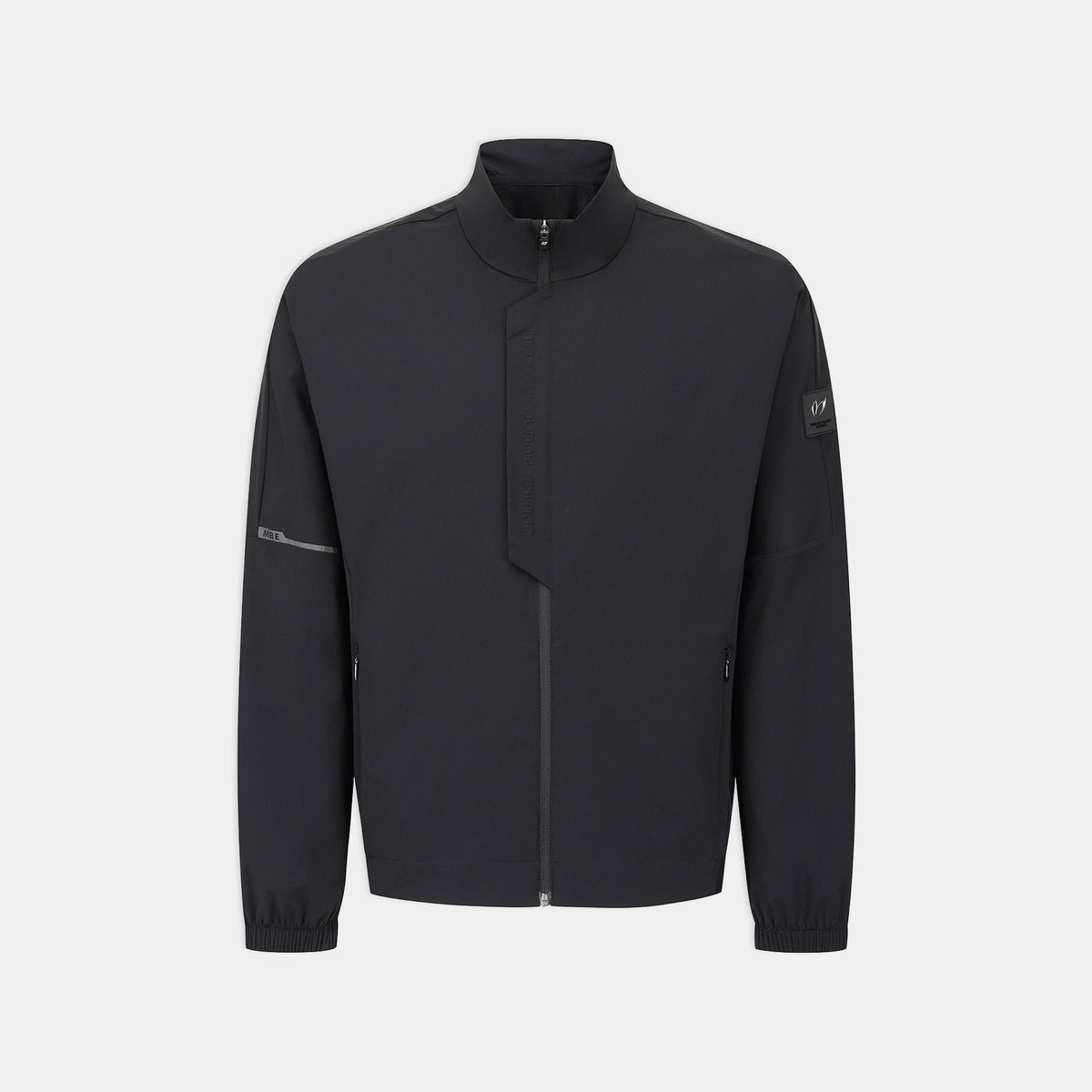 A dark charcoal gray zip-up jacket with a stand-up collar, shown on a light gray background. The jacket features a subtle diagonal seam across the chest, zippered cuffs, and a small logo patch on the left sleeve.