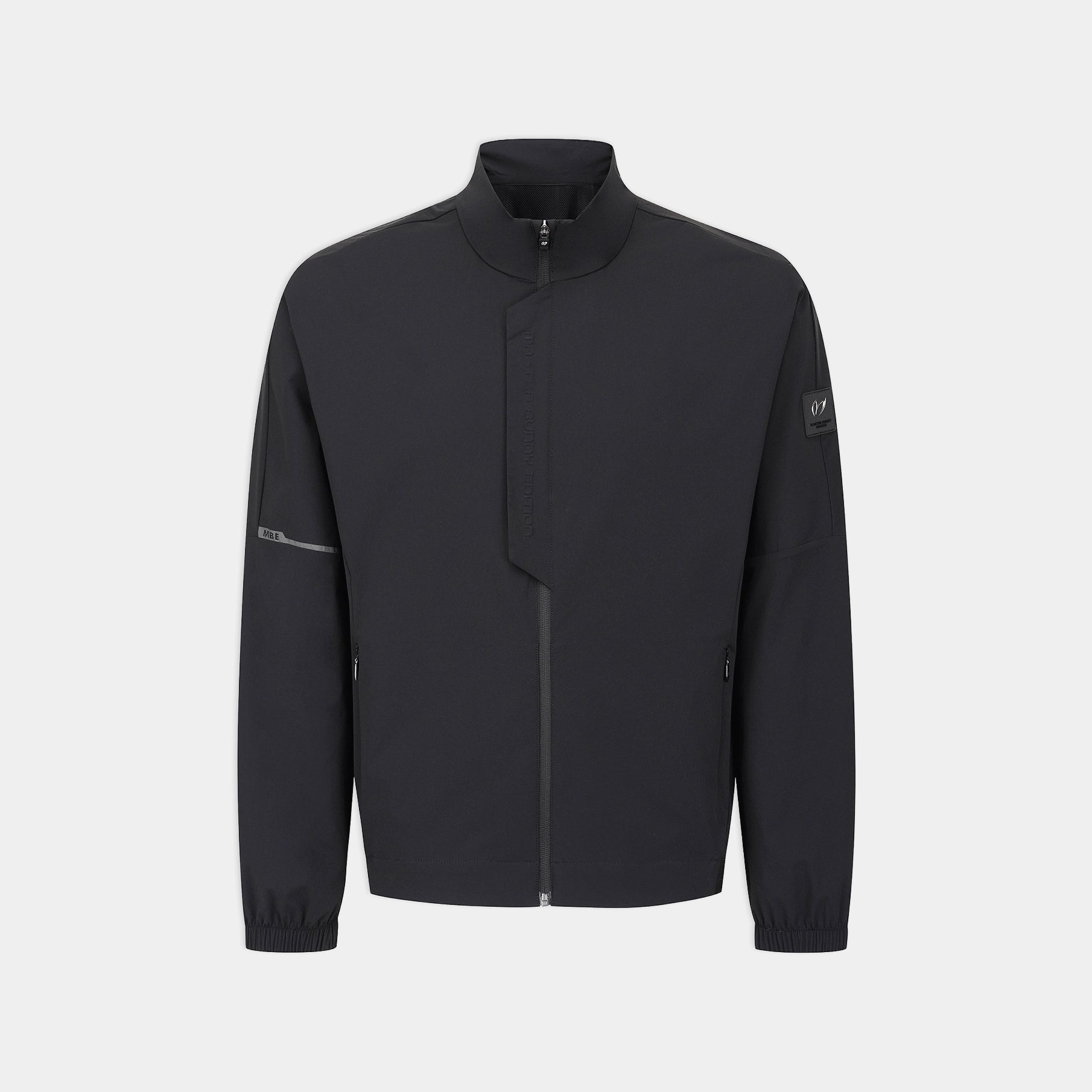 A dark charcoal gray zip-up jacket with a stand-up collar, shown on a light gray background. The jacket features a subtle diagonal seam across the chest, zippered cuffs, and a small logo patch on the left sleeve.