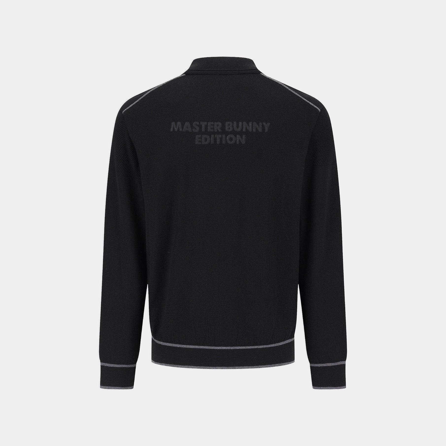 Black long-sleeve track jacket shown from the back, featuring a subtle dark gray 'MASTER BUNNY EDITION' logo printed across the upper back and thin gray piping details along the shoulders, hem, and cuffs, set against a light gray background.