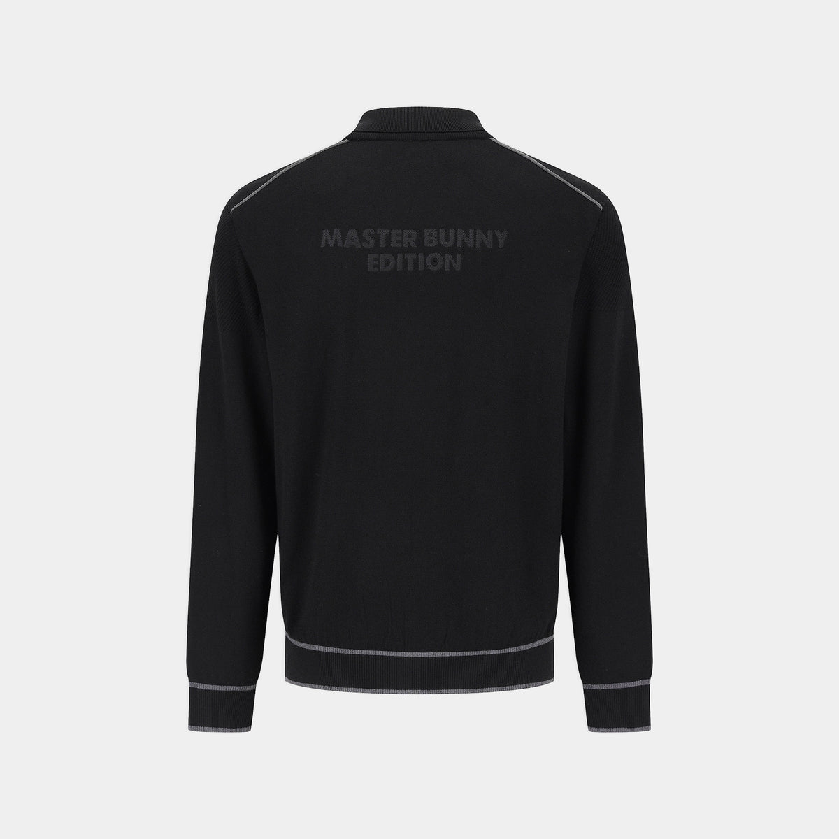 Black long-sleeve track jacket shown from the back, featuring a subtle dark gray 'MASTER BUNNY EDITION' logo printed across the upper back and thin gray piping details along the shoulders, hem, and cuffs, set against a light gray background.
