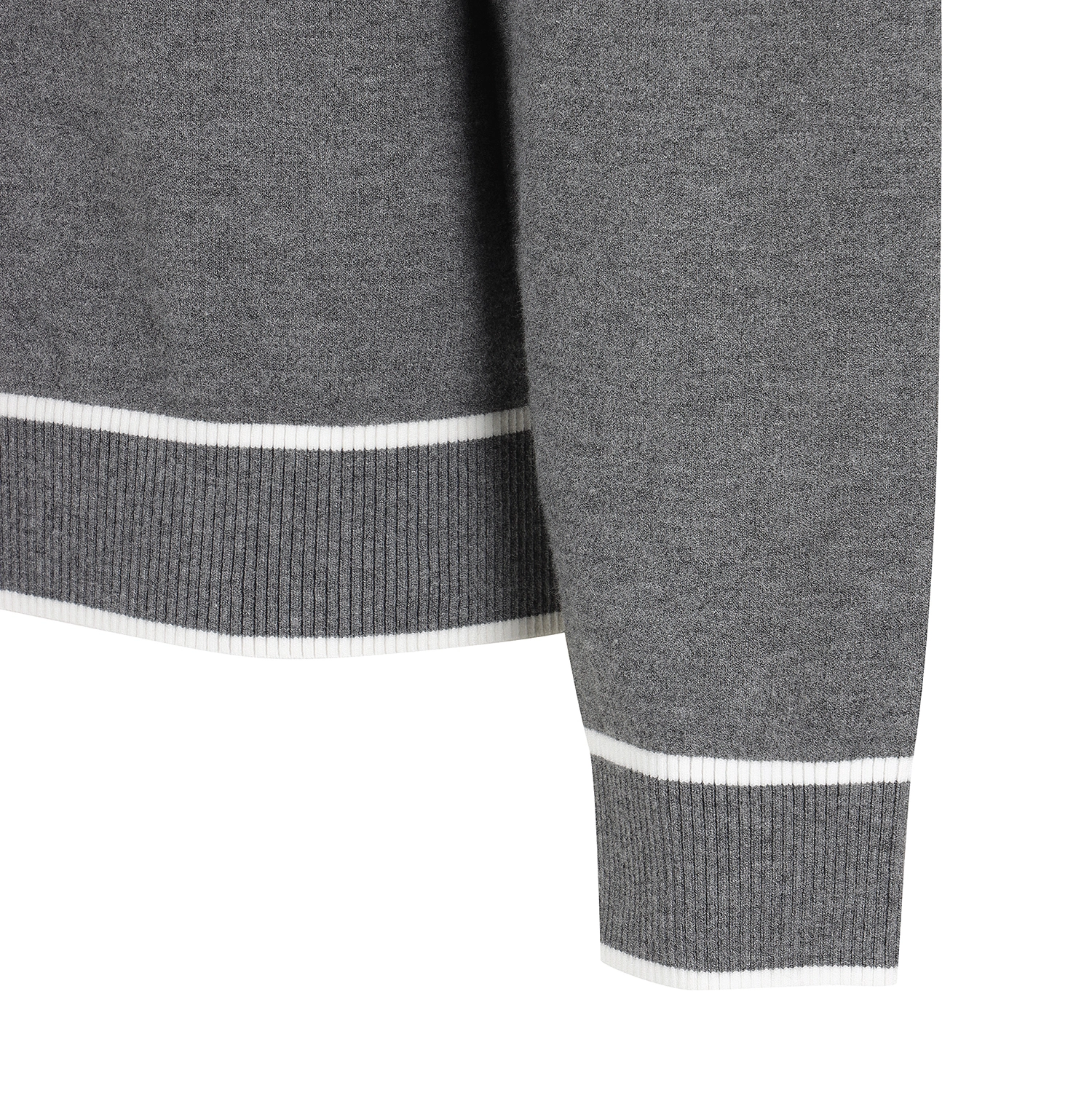 Close-up of a dark gray knit sweater sleeve showing a white ribbed trim at the cuff and hem against a white background.