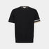 A black short-sleeve knit crewneck sweater with a small tonal embroidered logo on the left chest and beige and white striped detailing on the sleeve cuffs, shown against a light gray background.