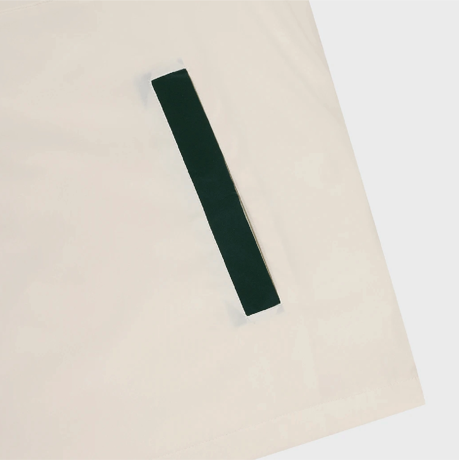 A dark forest green fabric hair tie or elastic band laid diagonally on a light cream-colored fabric surface.
