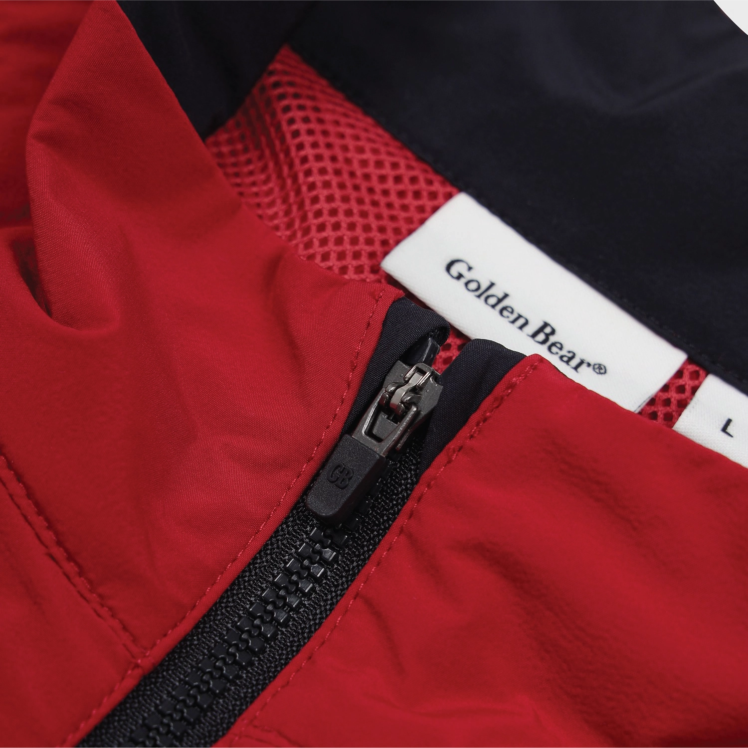 Close-up of a red jacket with a black zipper, black mesh lining, and a white sewn-in label reading Golden Bear.