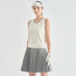 A model wearing a sleeveless off-white athletic tank top, a gray pleated tennis skirt, a white visor, and a white golf glove, standing against a light gray studio background.