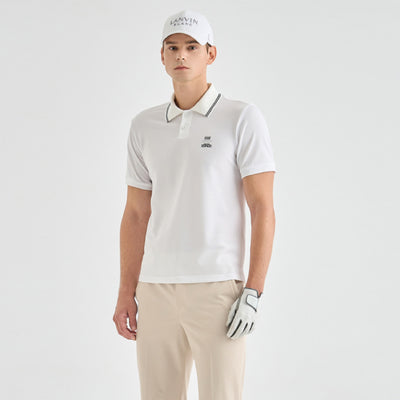 A man modeling a white short-sleeve polo shirt with a dark gray striped collar, paired with beige trousers, a white cap, and a white golf glove against a light gray studio background.