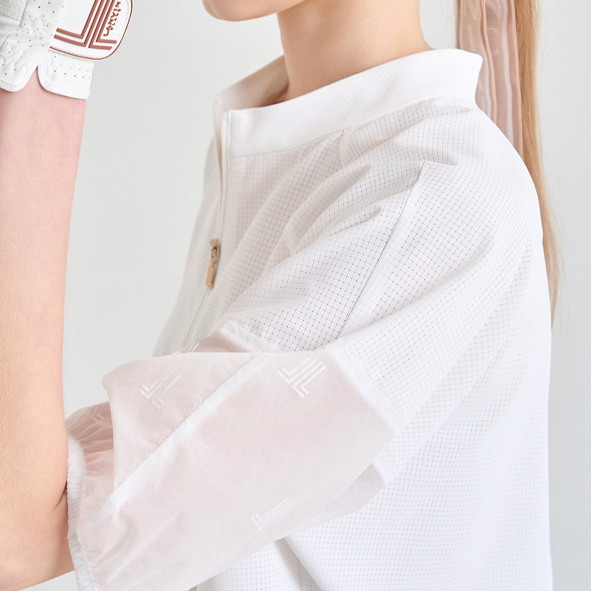 Close-up of a model wearing a white textured short-sleeve collared top with sheer flutter sleeves and a small gold button at the collar.