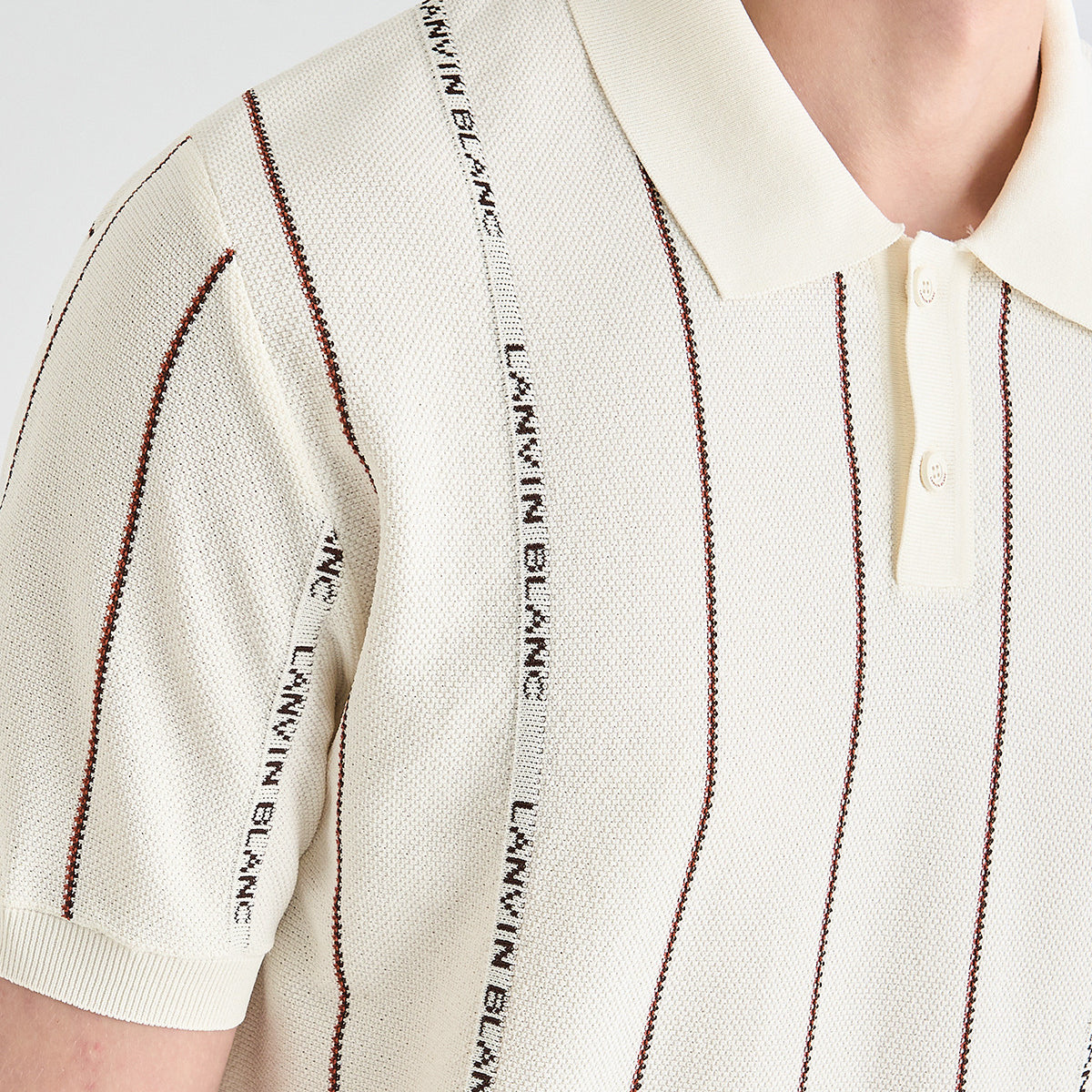 Close-up of a cream knit polo shirt with vertical dark brown stripes and a central white stripe printed with the brand name 'LANVIN BLANC'.