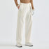 A model is shown from the waist down wearing high-waisted, wide-leg cream cargo pants with a flap pocket on the left leg, styled with a tan long-sleeve top, white gloves, and white sneakers against a plain white studio background.