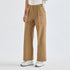 A person wearing tan wide-leg utility pants with a white top and white sneakers, shown from the waist down against a clean white studio background.