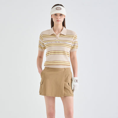 A woman modeling a beige and brown striped polo shirt with a matching beige visor, tan cargo skirt, and white golf glove against a light gray studio background.