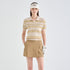 A woman modeling a beige and brown striped polo shirt with a matching beige visor, tan cargo skirt, and white golf glove against a light gray studio background.