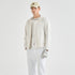 A man modeling a light beige outdoor jacket, white pants, a beige baseball cap, and a white glove against a plain white studio background.