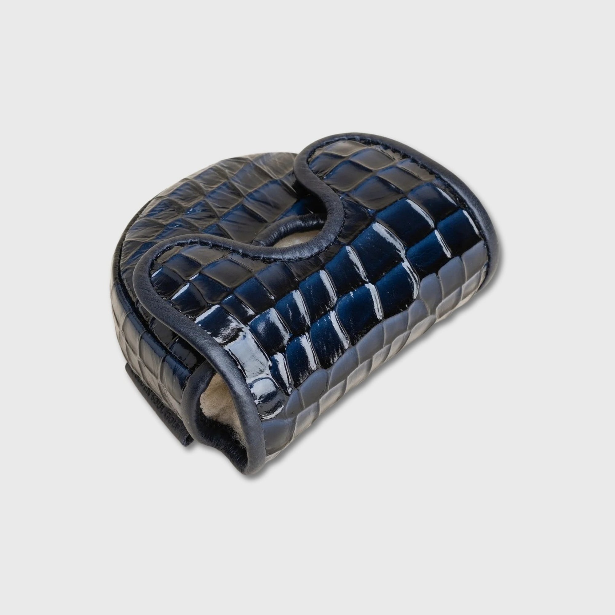 A glossy dark blue crocodile-embossed leather golf club cover on a light gray background.