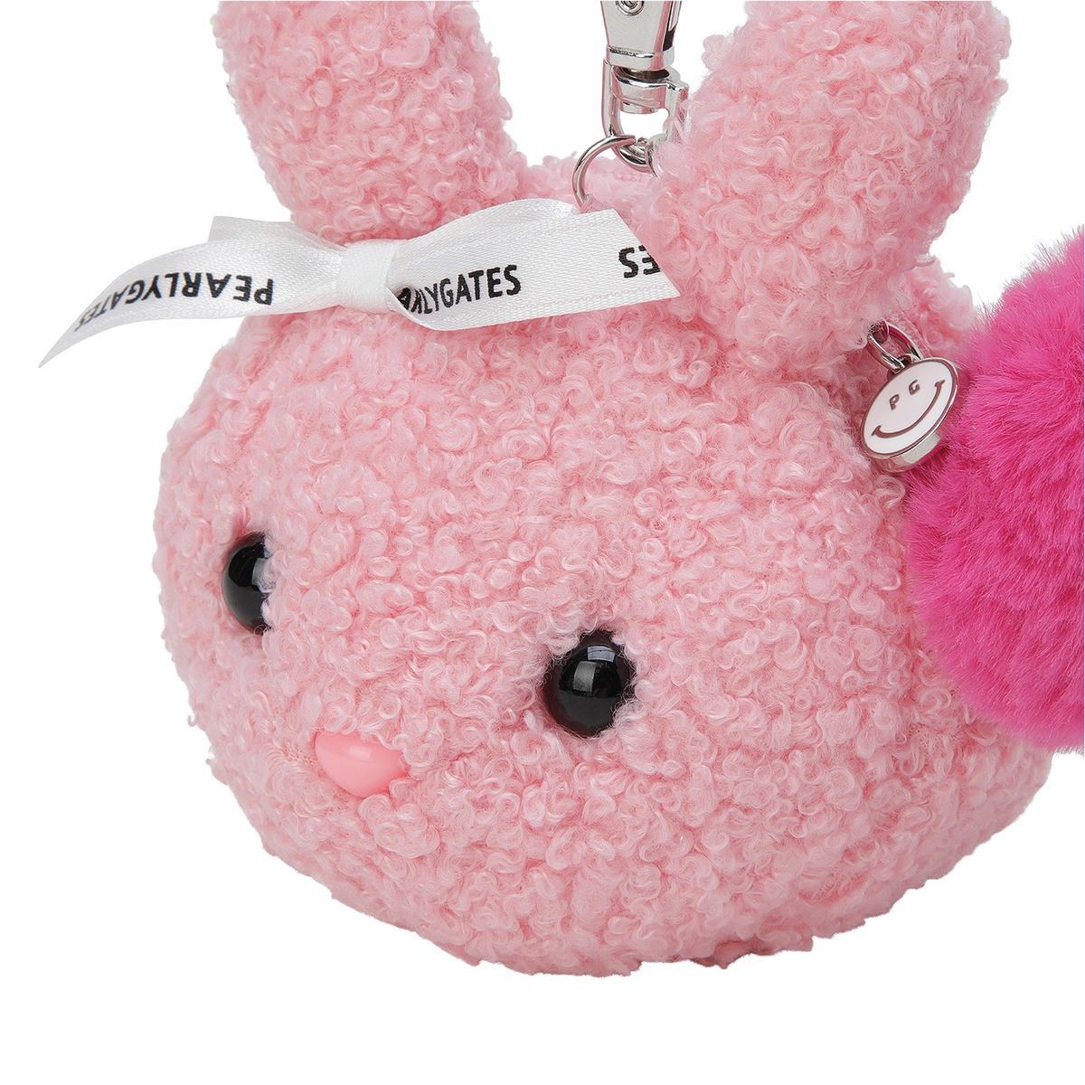 A pink plush bunny keychain charm with a textured bouclé fabric body, black bead eyes, a small pink nose, a white ribbon with black text, and a bright pink fluffy accent on the side.