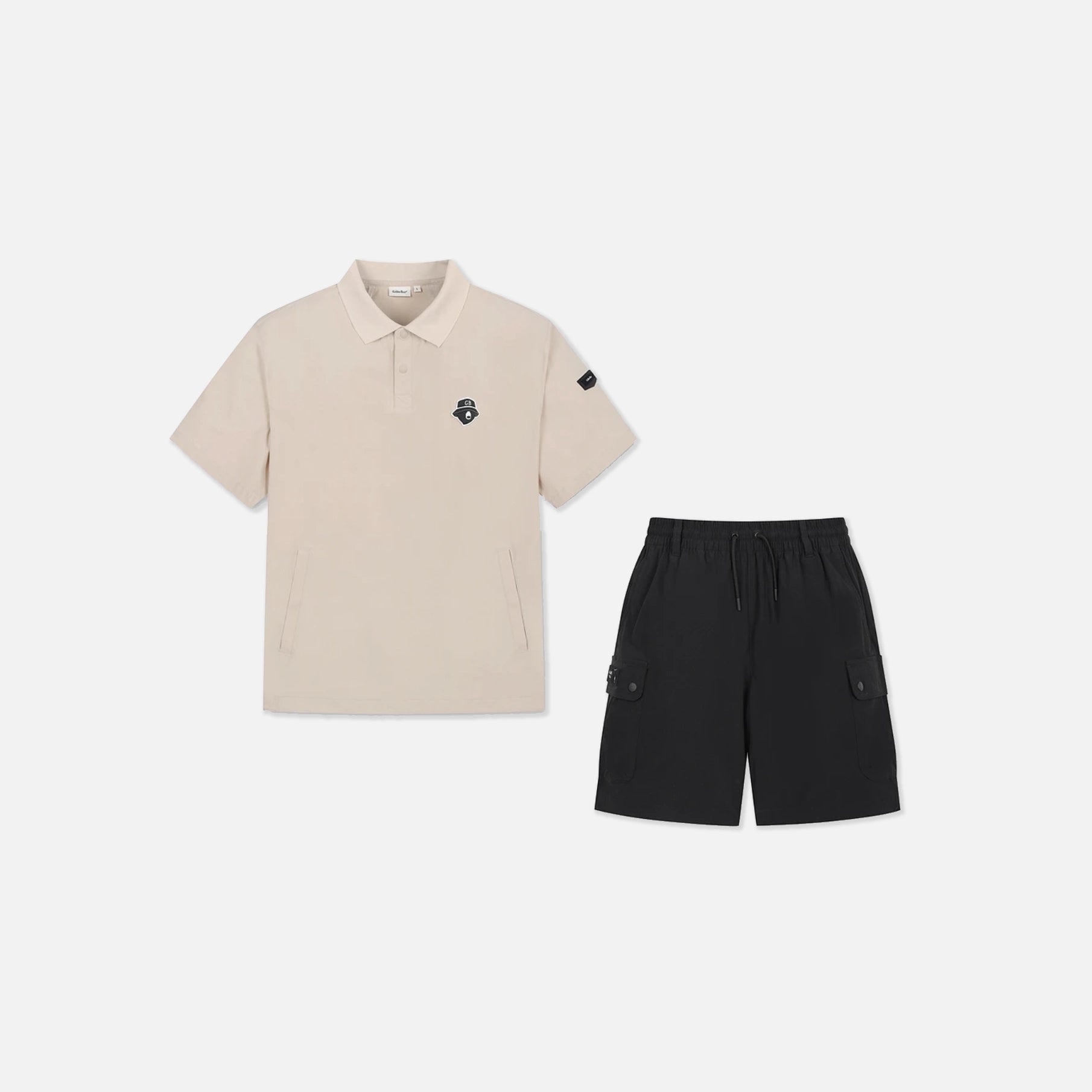 A two-piece adult' outfit set featuring a short-sleeve polo shirt in light beige with a small black embroidered logo on the left chest, paired with black cargo shorts, displayed on a clean light gray background.
