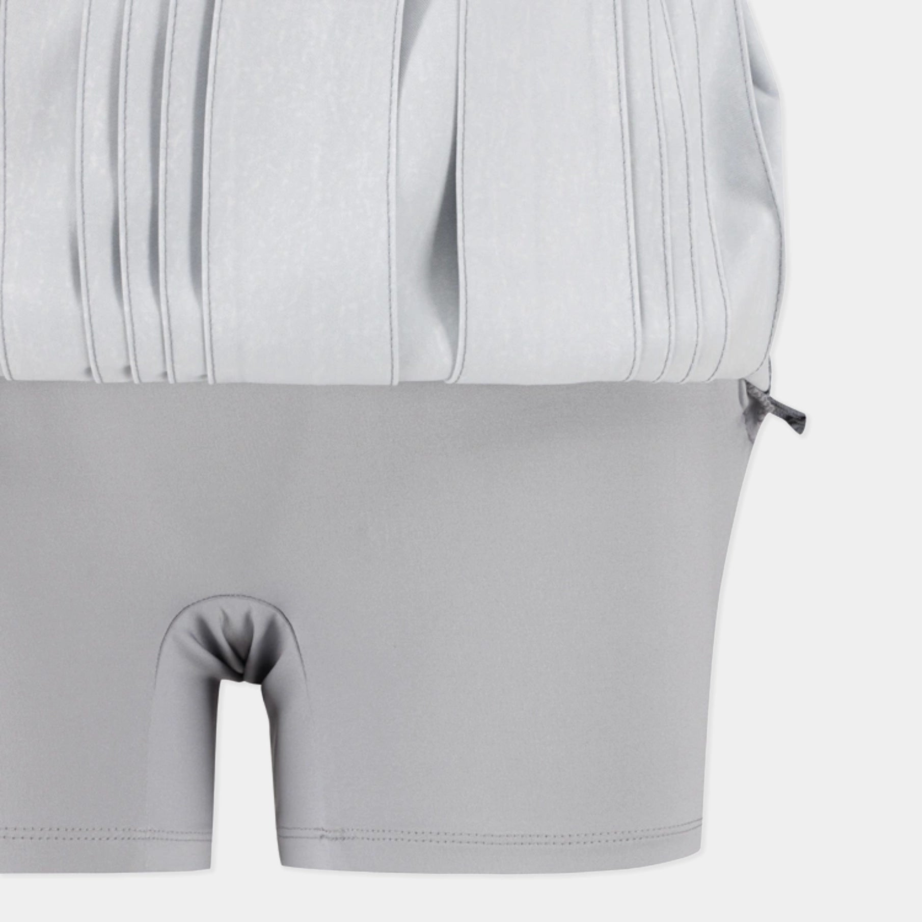Close-up of a light gray two-piece garment, showing a pleated top section and matching fitted shorts with a front split opening, on a plain light background.