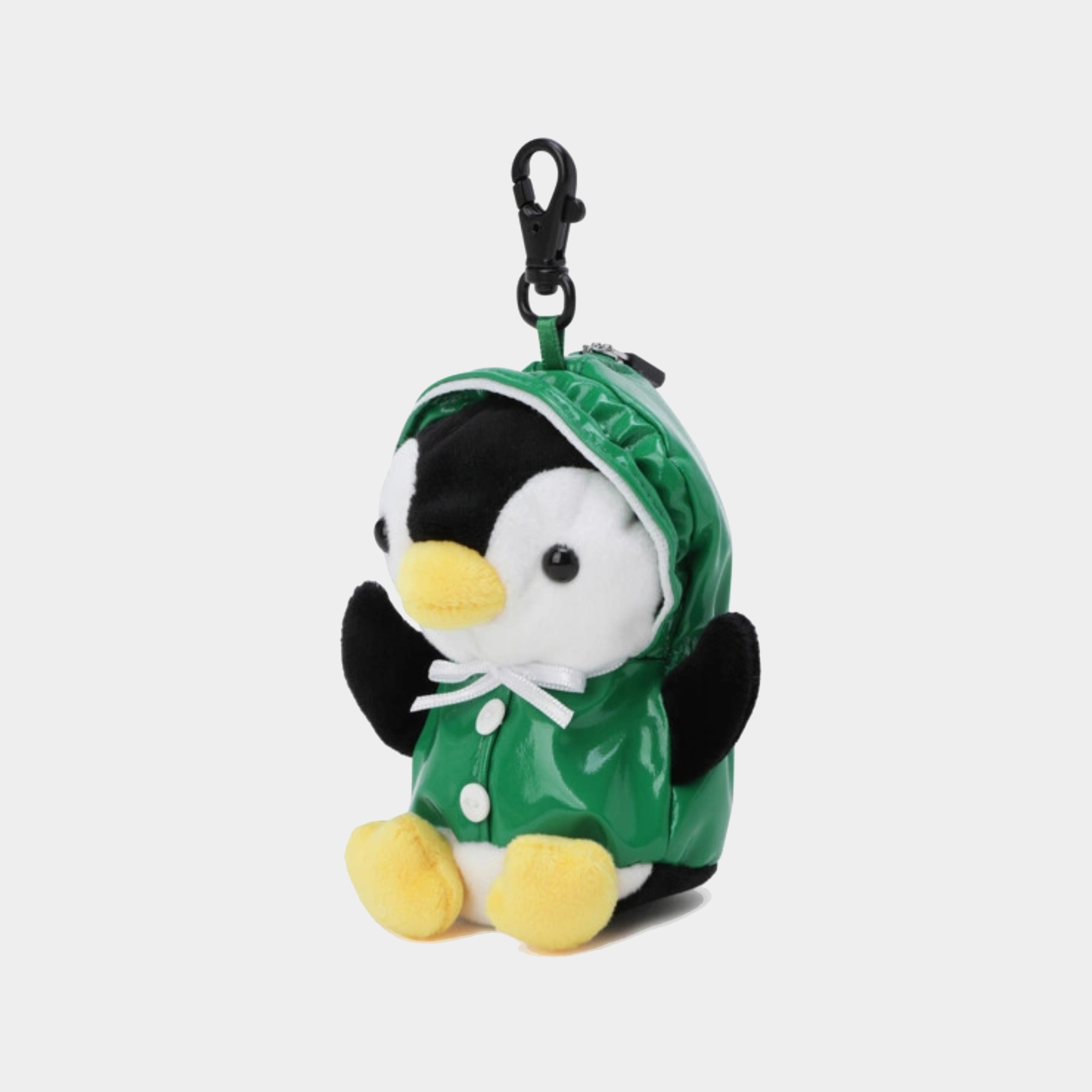 A plush penguin keychain or bag charm wearing a shiny green hooded raincoat with black and white body details, yellow beak and feet, and a black plastic clasp at the top, shown on a light gray background.