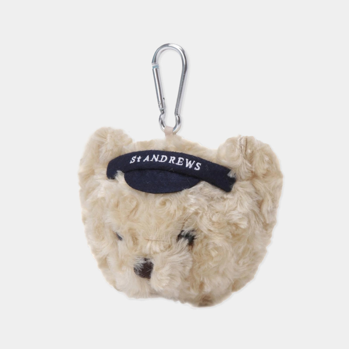 A plush teddy bear head keychain or bag charm in cream-colored curly fur, featuring a black fabric headband with 'St ANDREWS' embroidered in white, attached to a silver carabiner, on a light gray background.