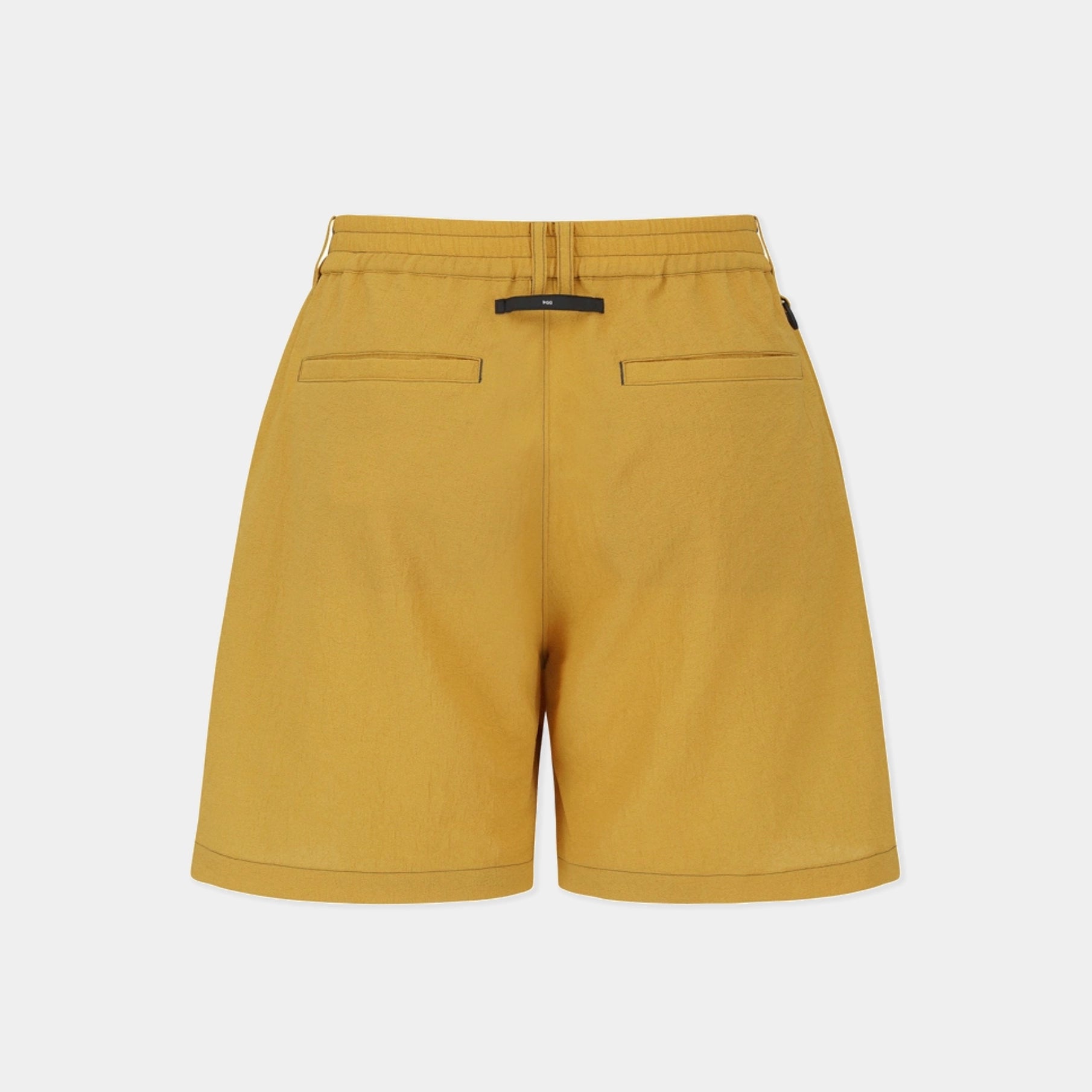 A pair of mustard yellow shorts shown from the back, featuring a drawstring waist, two welt back pockets, and a small black brand tab at the center back, set against a plain light gray background.