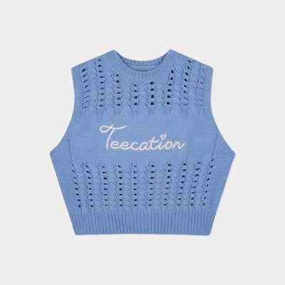 A light blue sleeveless knit crop top sweater vest with a white cursive embroidered logo reading 'Teecation' on the chest, displayed flat against a light gray background.