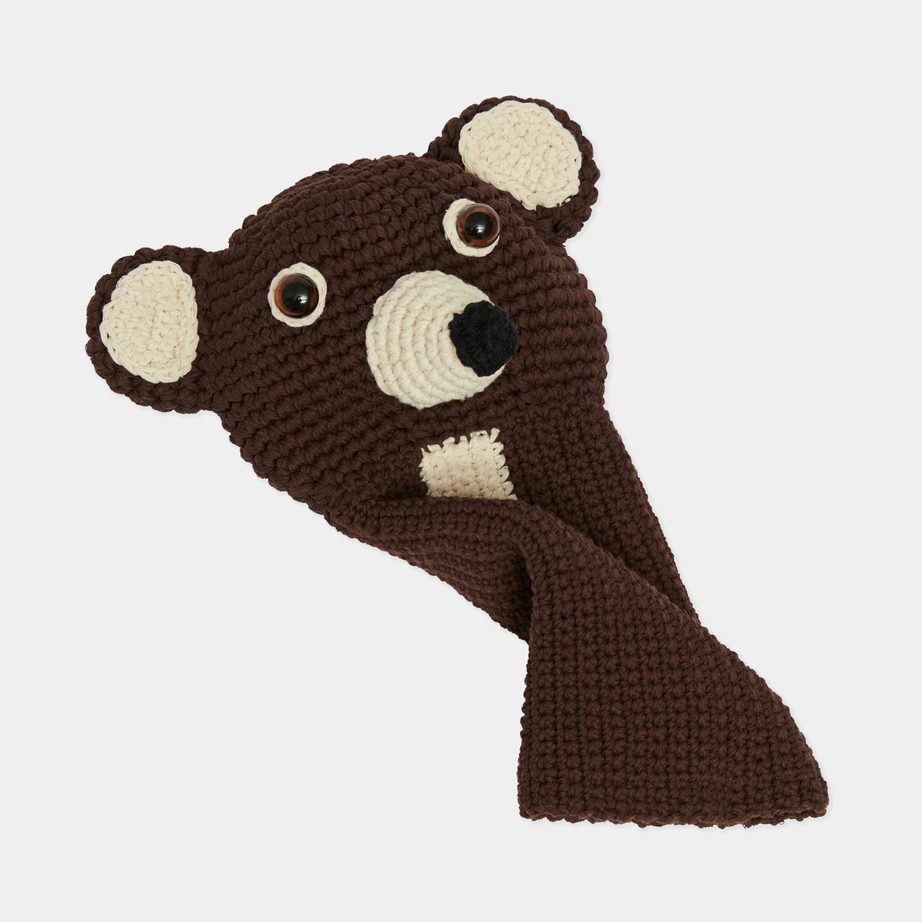 A brown crocheted bear head and neck pillow with cream-colored ears, inner ears, and chest patch, set against a plain light gray background.