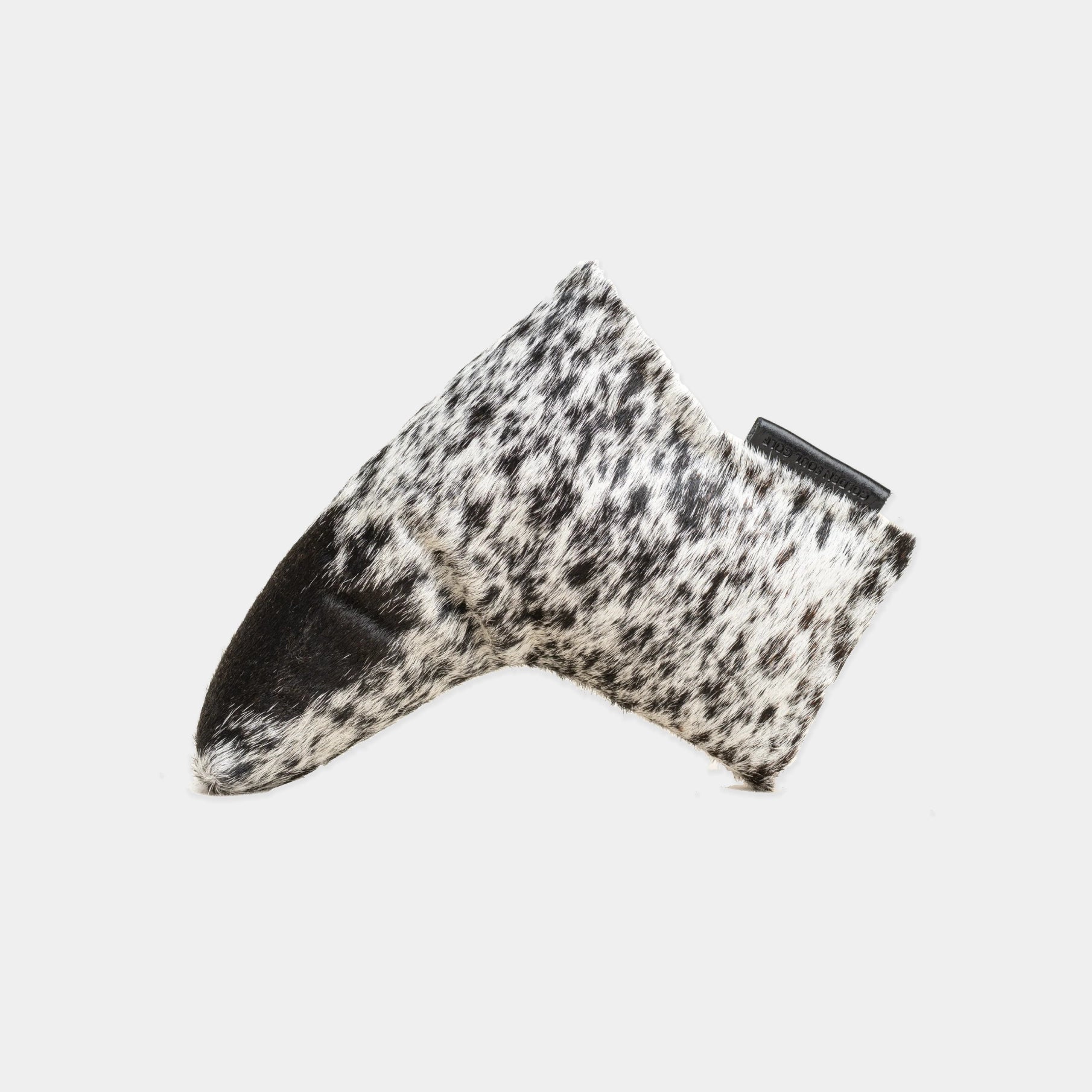 A putter cover in black and white cowhide with a solid black toe cap, photographed on a light gray background.