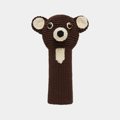 A crocheted bear head golf club headcover in dark brown and cream, featuring embroidered eyes and nose, shown against a light gray background.
