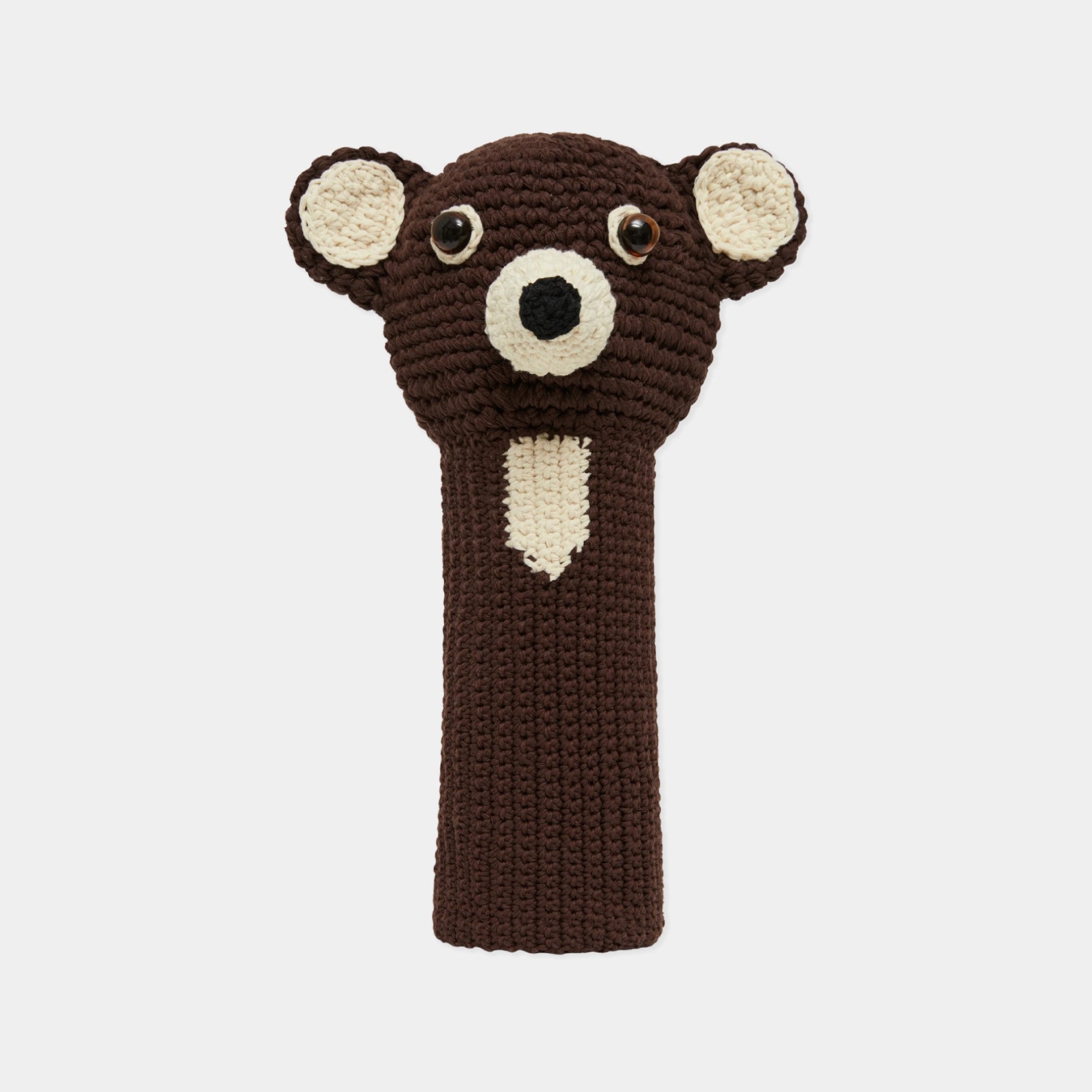 A crocheted bear head golf club headcover in dark brown and cream, featuring embroidered eyes and nose, shown against a light gray background.