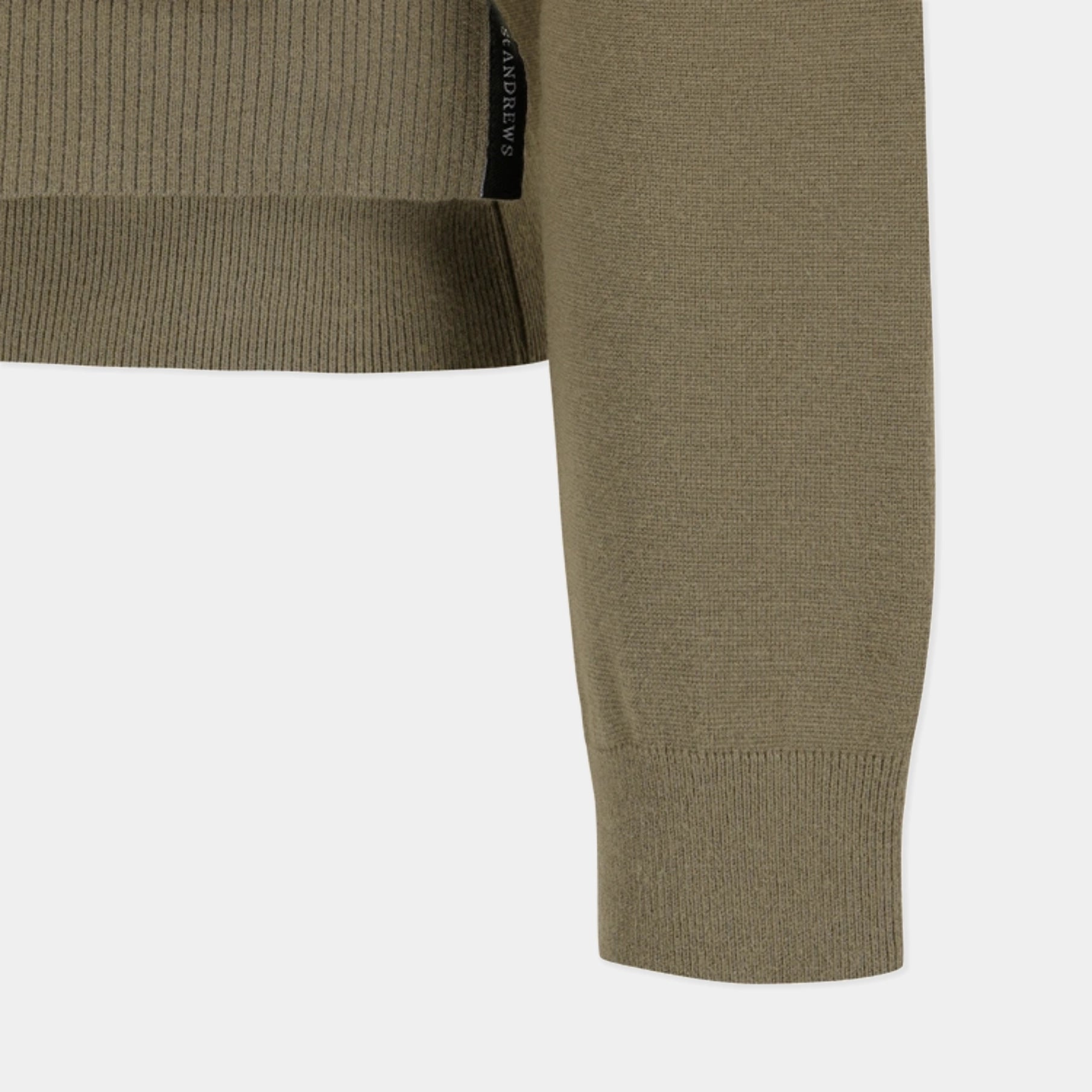 Close-up of a ribbed knit sweater sleeve in an olive green color, showing the ribbed cuff and a small black brand tag on the inner side.