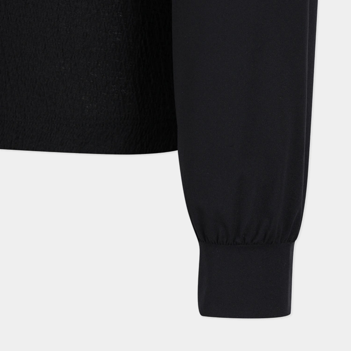 Close-up of a black long-sleeve top showing the sleeve and ribbed cuff against a light gray background.