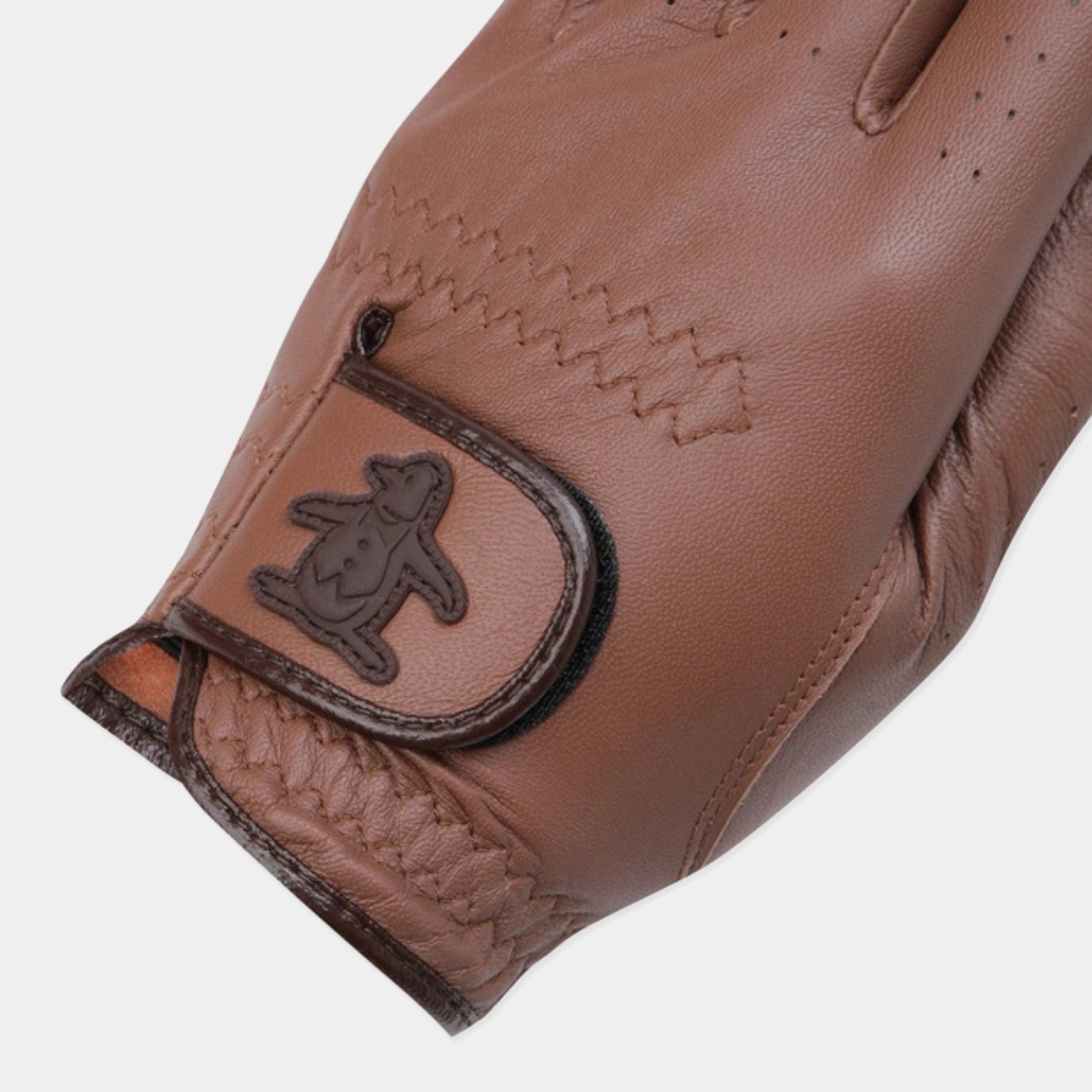 A close-up of a brown leather golf glove featuring a stitched chevron pattern, a braided cuff, and a dark brown embossed penguin logo patch on the wrist strap.