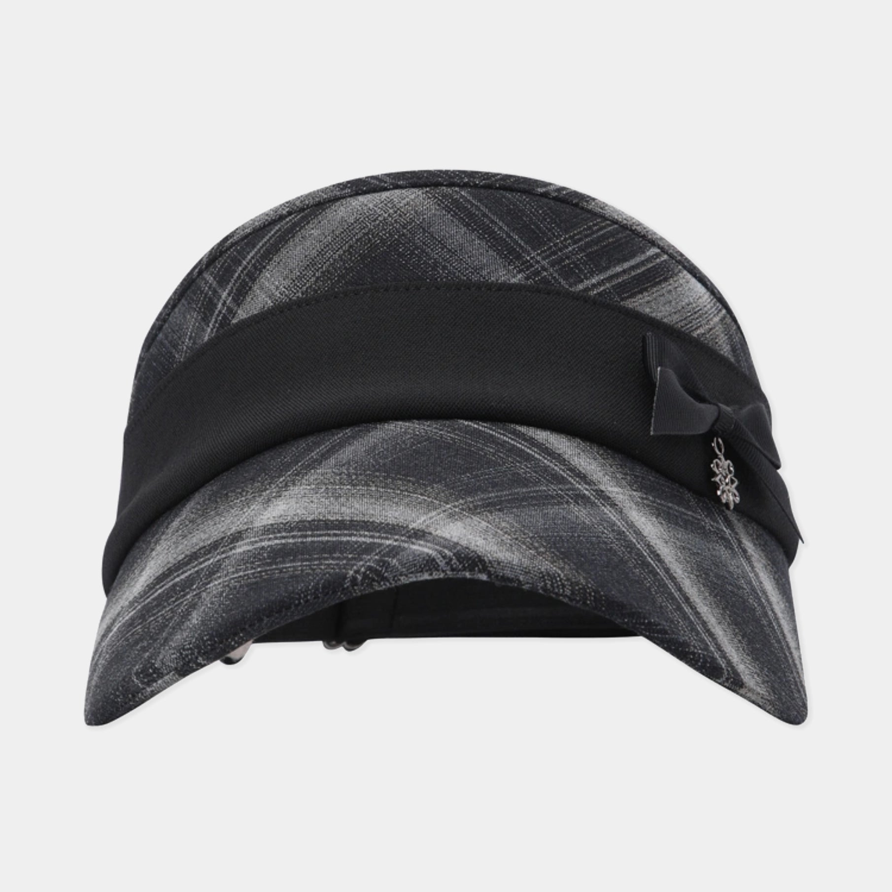 A black and gray plaid visor hat with a wide black band, a black bow, and a small silver floral charm, shown against a light gray background.