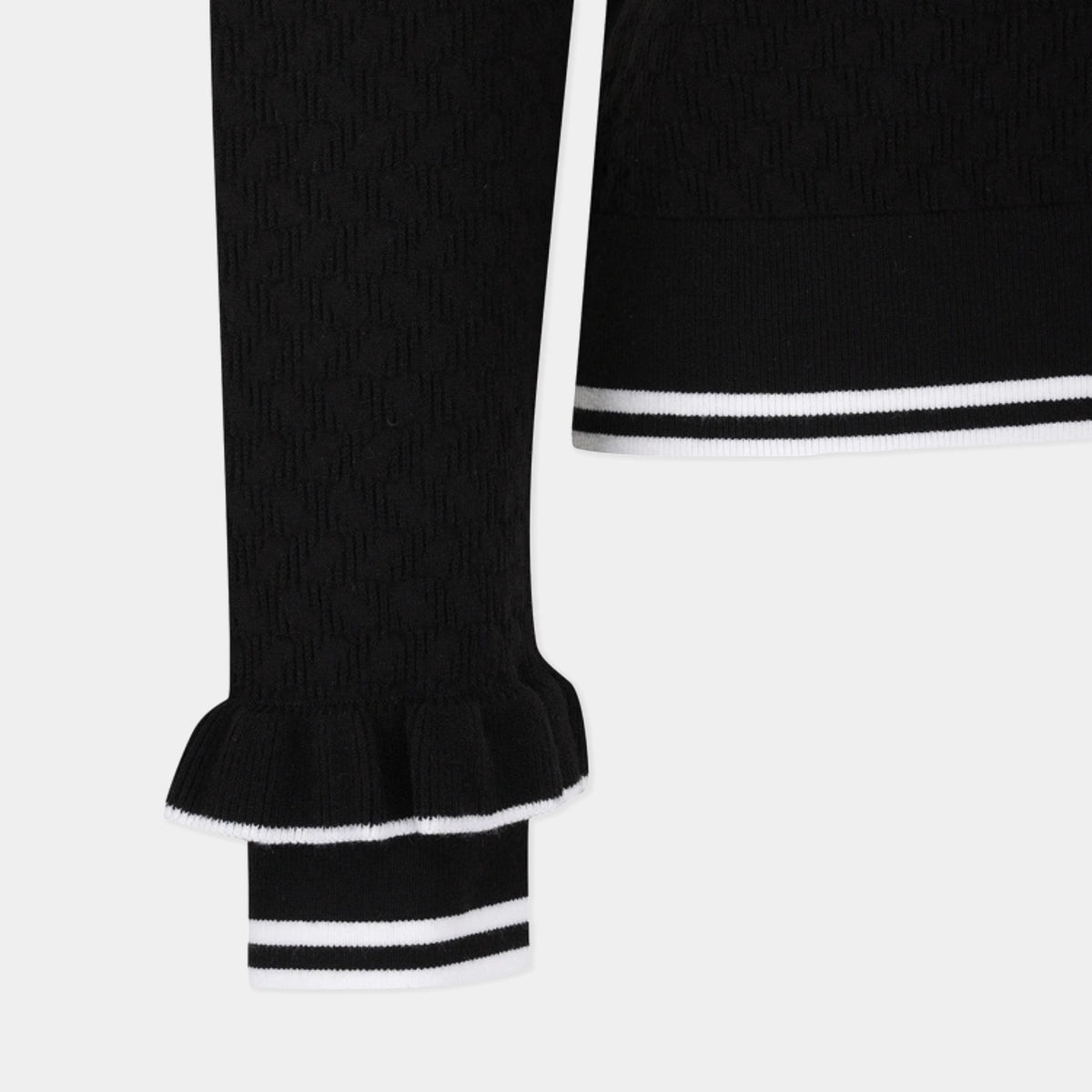 Close-up of a black ribbed knit garment with a ruffled cuff and white stripe trim, shown against a light gray background.