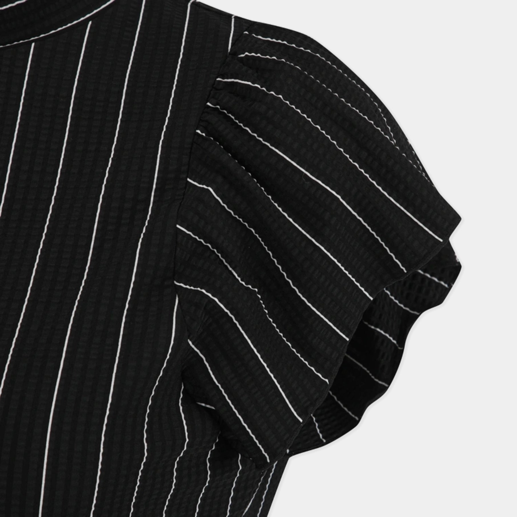 Close-up of a black textured top with white vertical pinstripes and a ruffled short sleeve, shown against a light gray background.