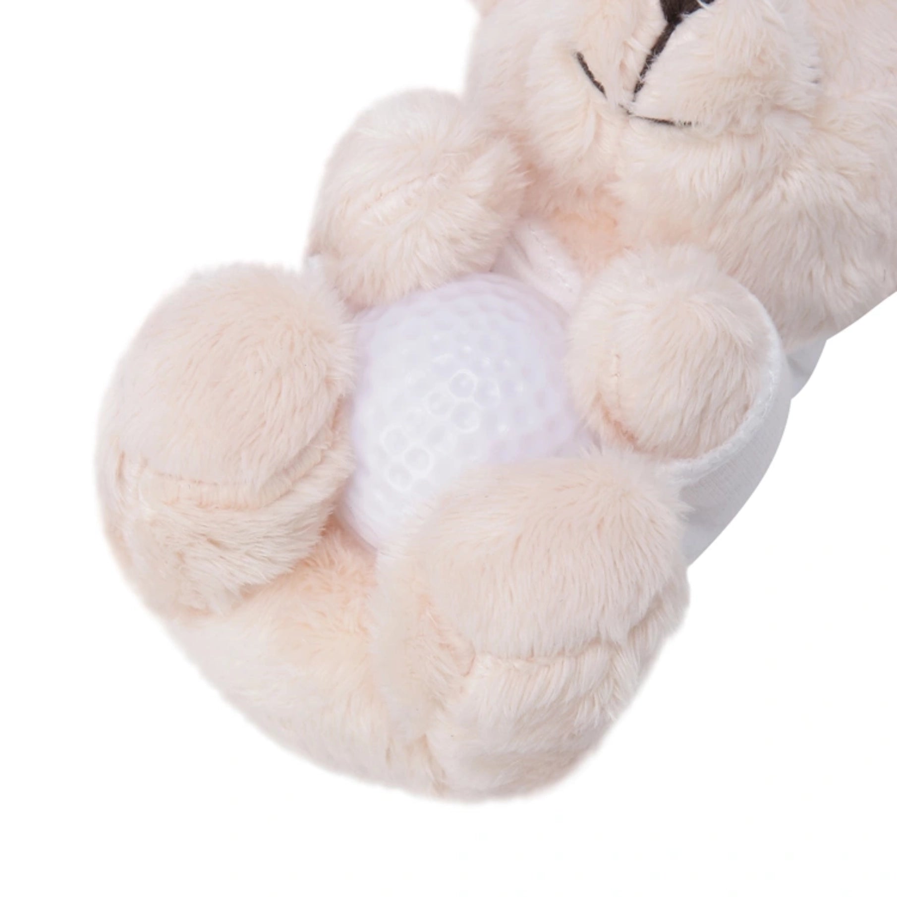 A close-up of a plush teddy bear holding a white golf ball, shown against a plain white background.