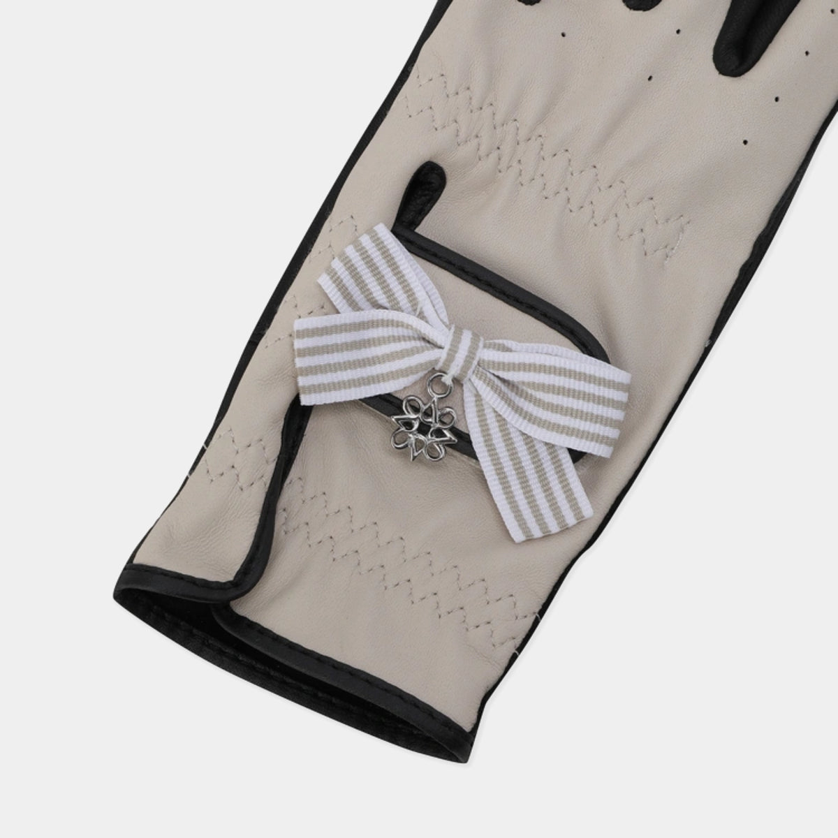 Close-up of the beige leather golf glove's ribbon detail and wrist area.