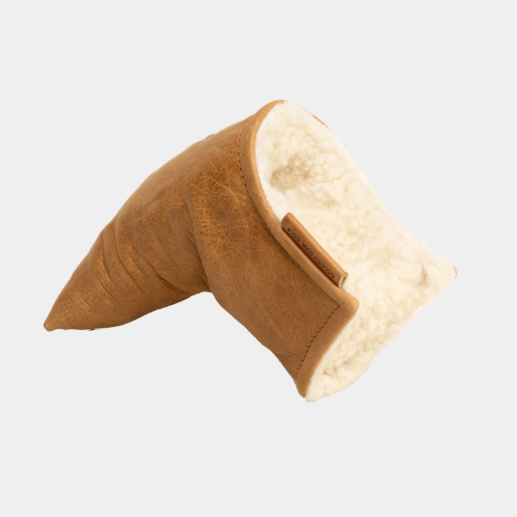 A tan leather blade putter cover with a cream-colored sherpa lining, shown on a light gray background.