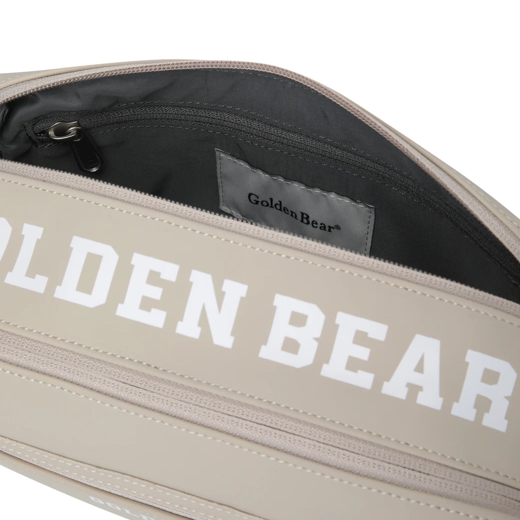 Close-up of a beige bag with large white 'GOLDEN BEAR' text across the front, shown open to reveal a dark gray interior and a Golden Bear brand label.