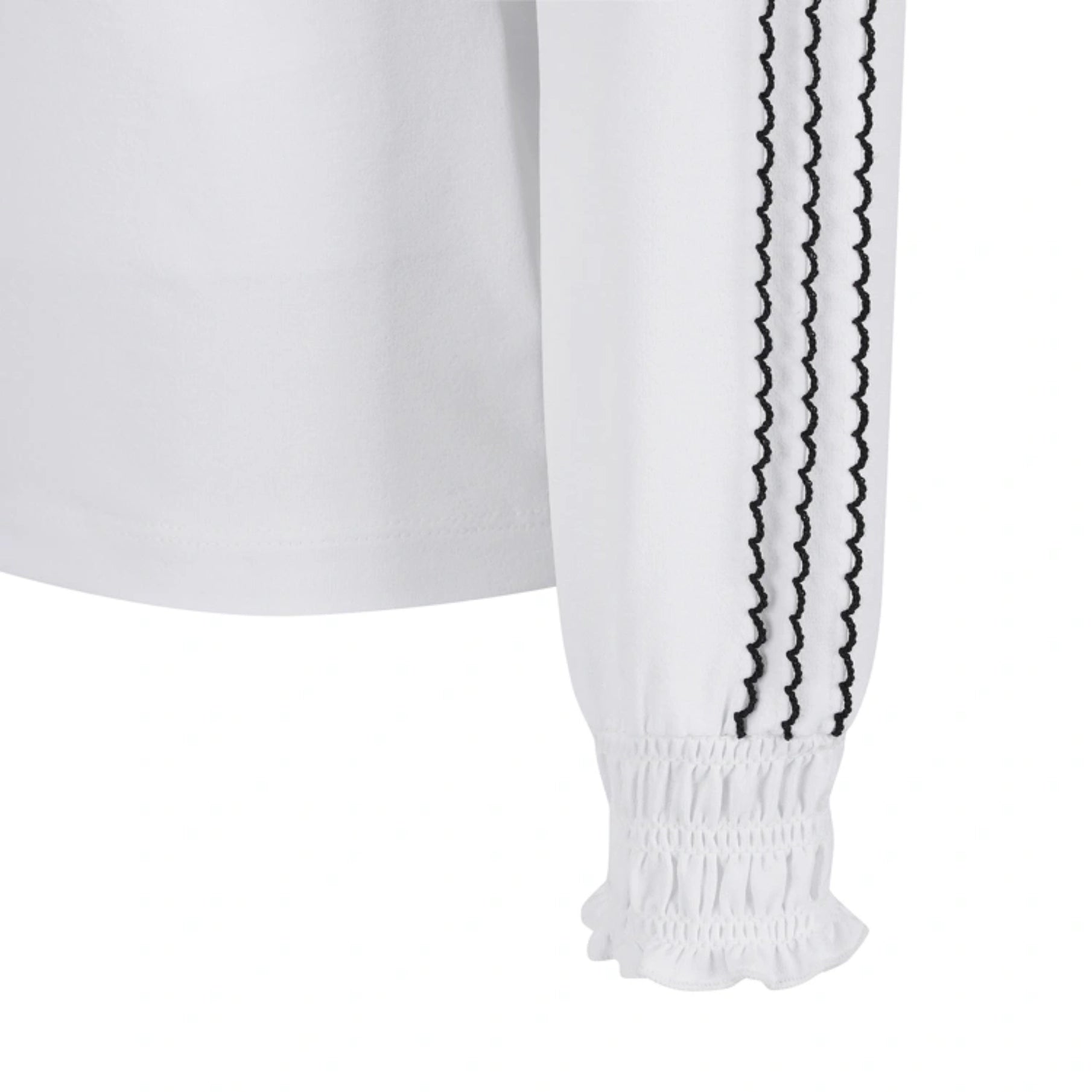 Close-up of a white long-sleeve top with black scalloped vertical stripes down the sleeve and a ruffled elastic cuff.